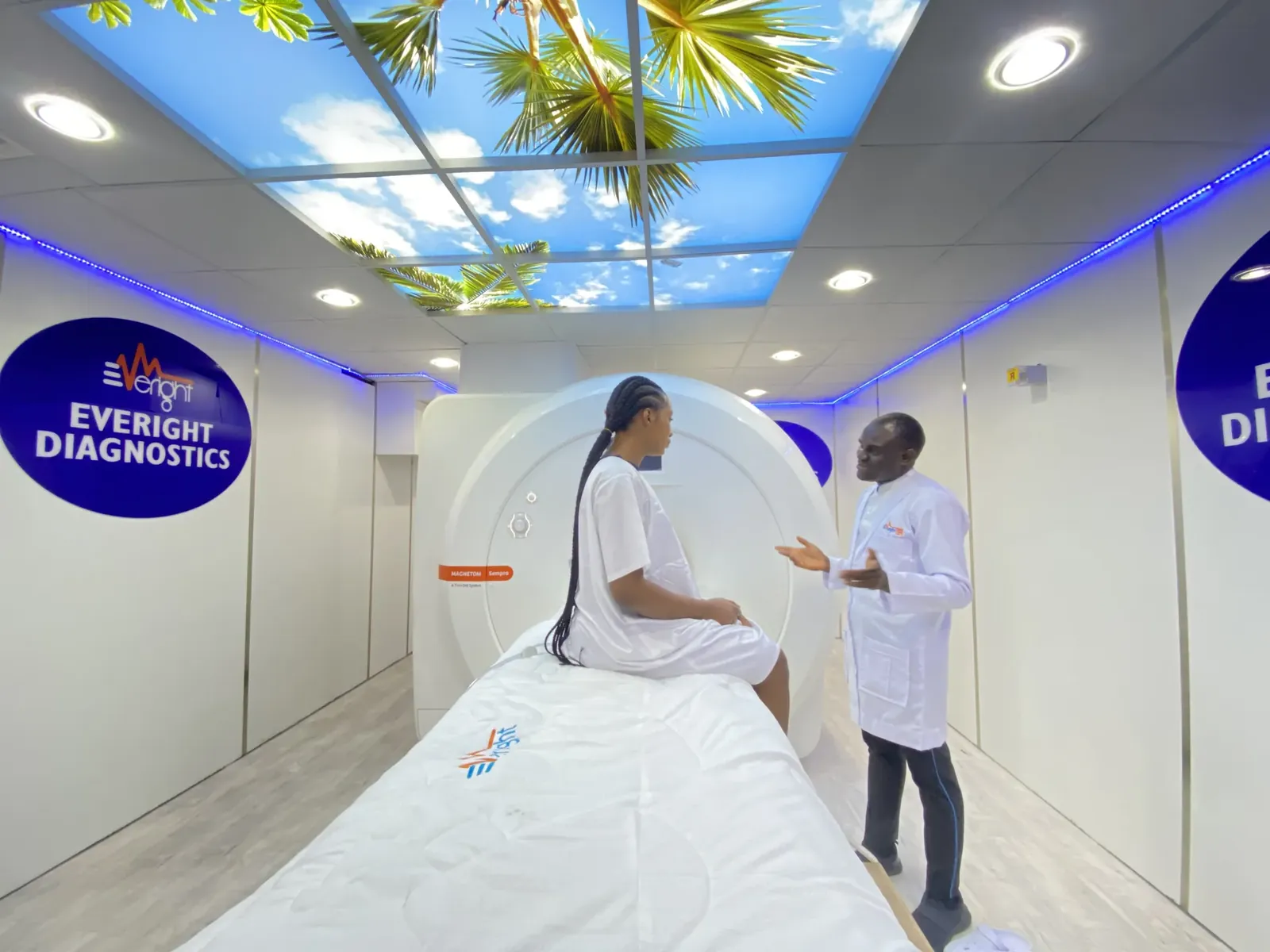 A patient on the scanner bed of Everight's 1.5 Tesla MRI while a radiographer explains the examination